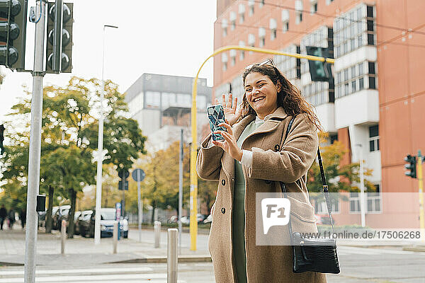 Happy plus size woman waving on video call through smart phone