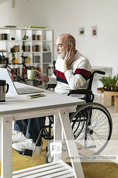 Senior businessman with physical disability looking at laptop on desk