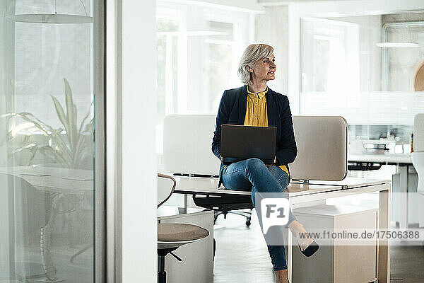 Businesswoman sitting with laptop on desk