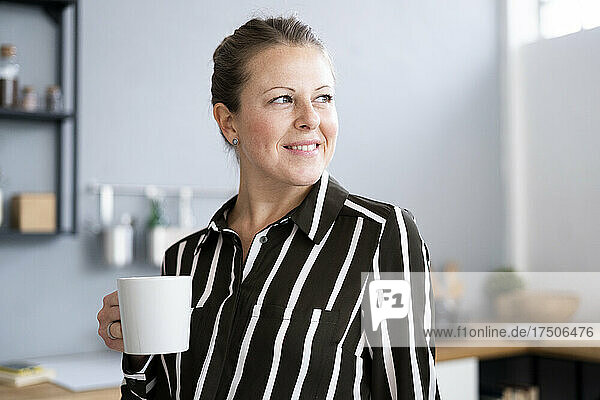 Thoughtful woman holding coffee cup at home