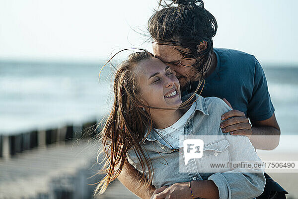 Liebevolles Paar umarmt sich am Strand