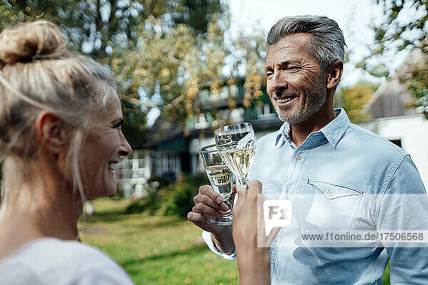 Lächelndes Paar prostet im Hinterhof mit Champagnerglas zu