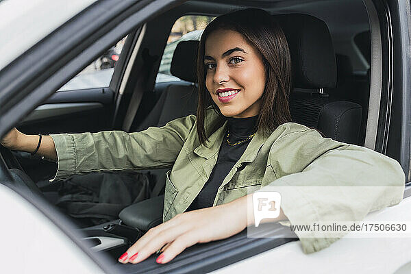 Happy young woman driving car