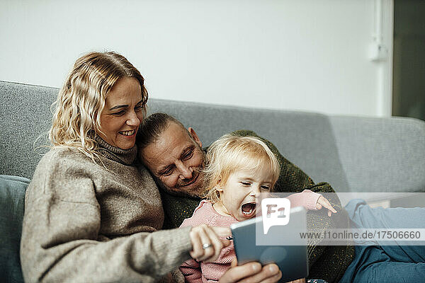 Happy family using tablet PC on sofa at home