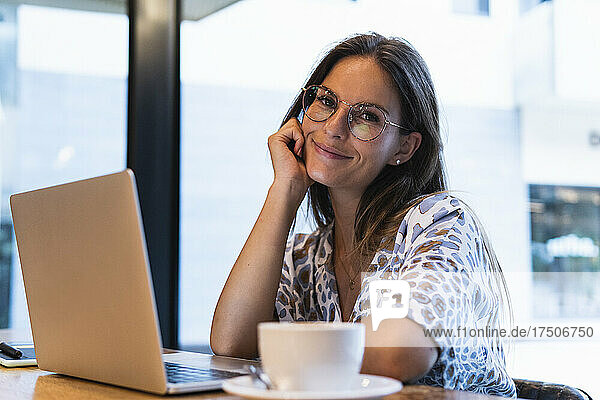 Beautiful businesswoman with laptop leaning on table