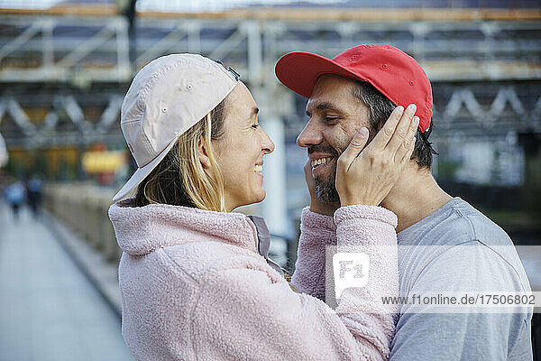 Happy woman touching boyfriend's face in city