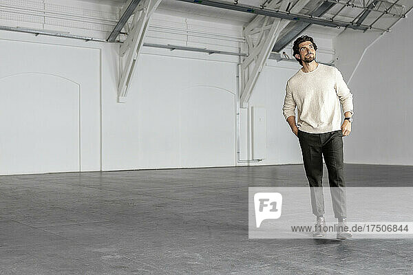 Businessman contemplating in empty industrial hall