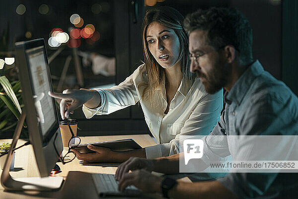 Businesswoman discussing strategy over computer with colleague in office at late night
