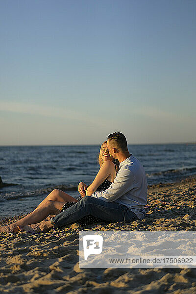 Junges Paar sitzt zusammen am Strand