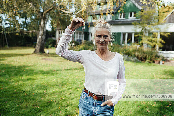 Woman with hand in pocket holding house key at backyard
