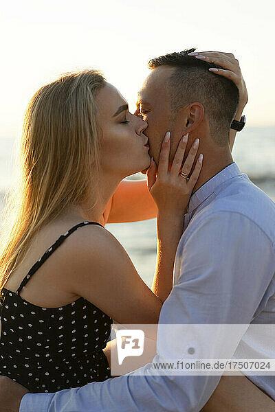 Blond woman kissing man at sunset