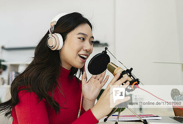 Young woman with headphones using microphone at home