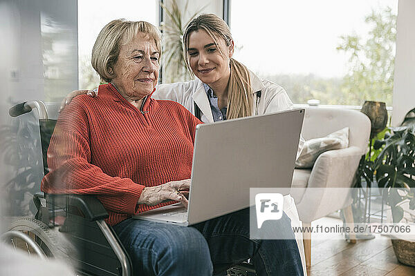 Disabled woman using laptop with nurse at home