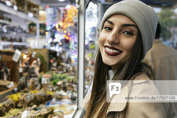 Junge Frau lächelt zur Weihnachtszeit im Geschäft