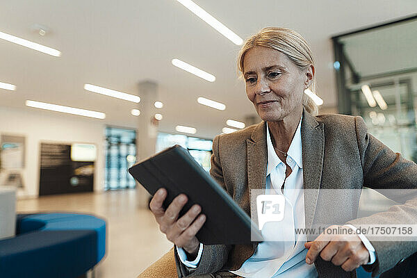 Smiling businesswoman using tablet PC in office lobby