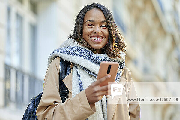 Young woman with bag holding smart phone