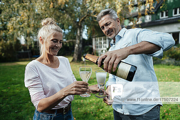 Mann schenkt Frau im Hinterhof Champagner ein