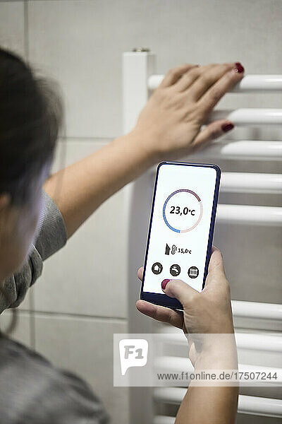 Frau regelt die Temperatur per Handy am Heizkessel