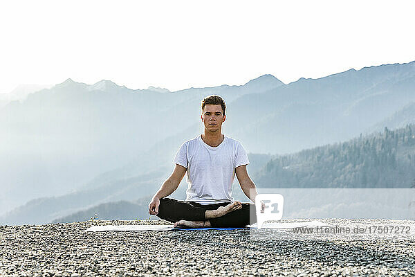 Man meditating in lotus position with mountain view