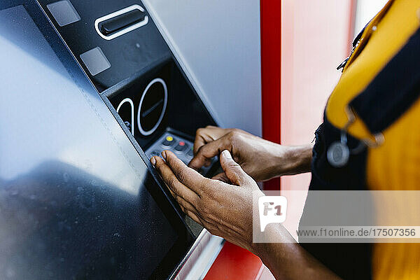 Frau gibt PIN in Geldautomaten ein