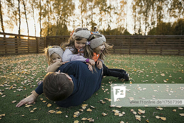 Siblings playing with father at lawn in autumn