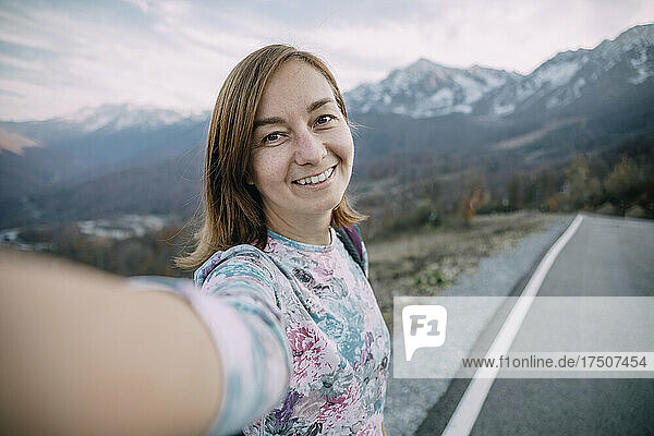 Smiling hiker taking selfie on mountain road