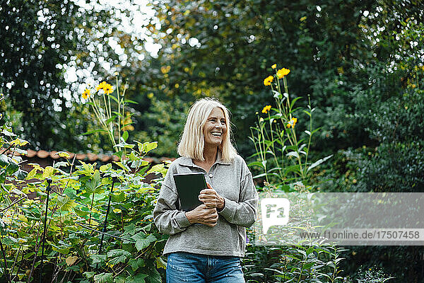 Smiling woman holding tablet PC at garden