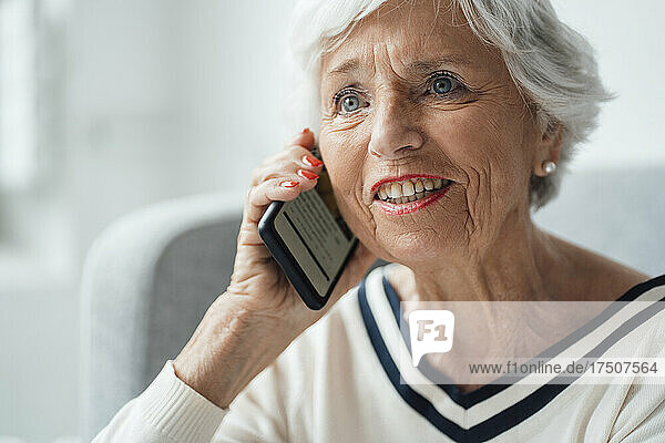 Smiling woman talking on smart phone at home