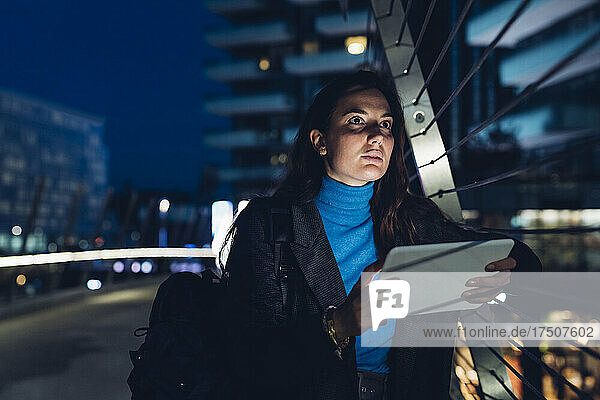 Thoughtful businesswoman with tablet PC leaning on railing