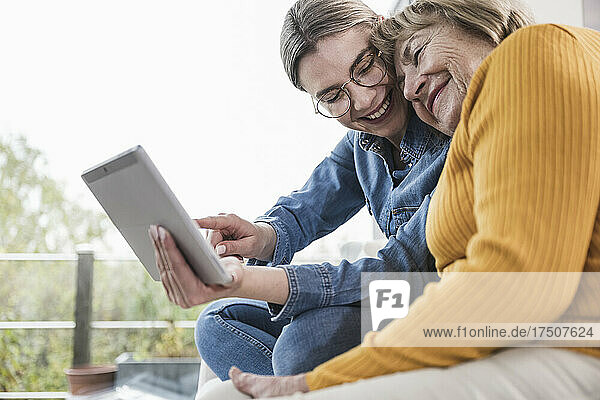 Smiling caregiver using tablet PC with senior woman at home