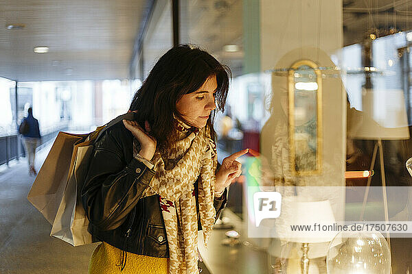 Woman with shopping bags doing window shopping at electric lamp store