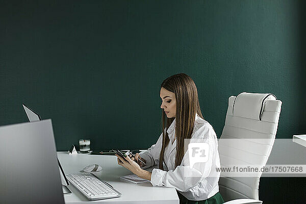 Businesswoman using smart phone at desk in office