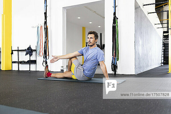 Sportsman practicing stretching exercise in gym