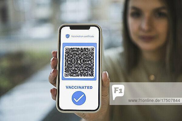 Woman holding mobile phone with QR code and check mark symbol on screen