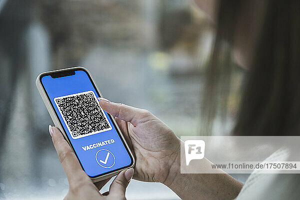 Young woman with vaccination QR code on smart phone screen