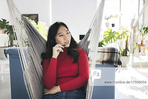 Young businesswoman talking through headset on hammock
