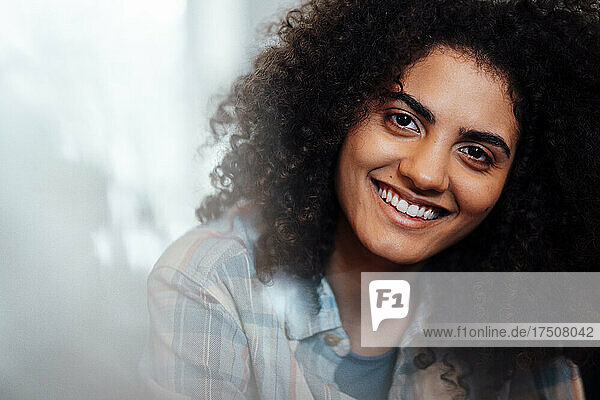 Glückliche junge Frau mit lockigem Haar lächelnd