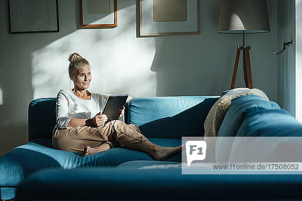 Woman holding tablet PC in living room at home