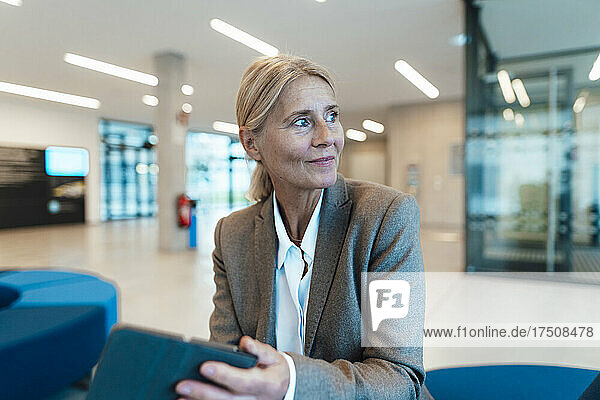 Thoughtful businesswoman with tablet PC at office lobby