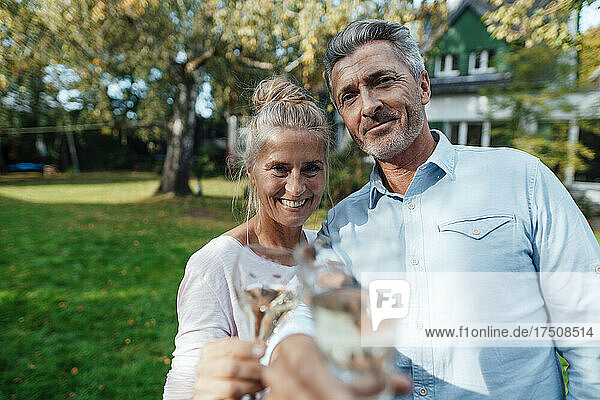 Smiling couple holding drinks at backyard