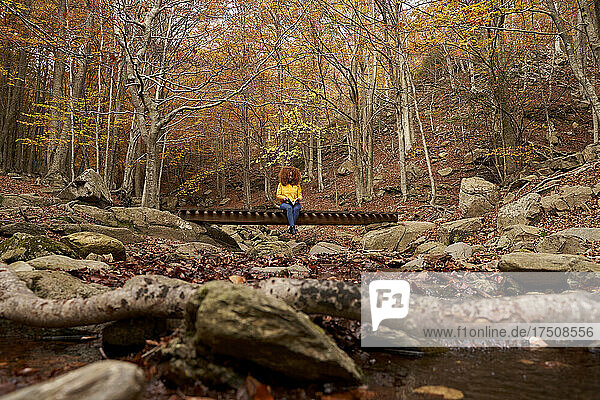 Young woman reading book in autumn forest