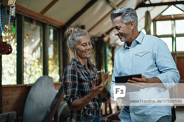 Smiling couple using tablet PC at garden shed