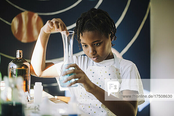 Mädchen mischt eine Chemikalie in einem Becherglas  während sie ein wissenschaftliches Experiment zu Hause durchführt