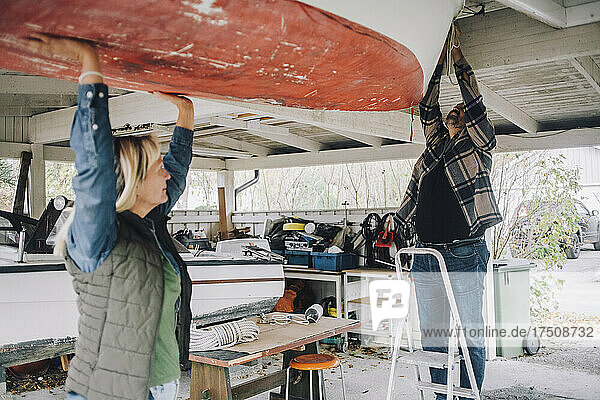 Älterer Mann bindet ein nautisches Schiff  während eine Freundin ihm in der Garage hilft