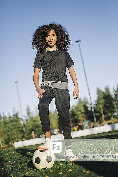Porträt eines Mädchens mit Fußball auf einem Sportplatz an einem sonnigen Tag