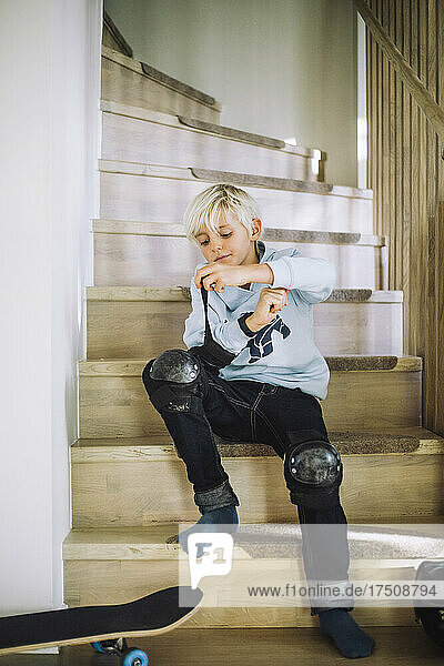 Junge trägt Ellbogenschützer  während er auf einer Treppe sitzt