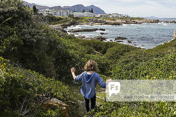 Young boy in a blue shirt walking on a path to the beach