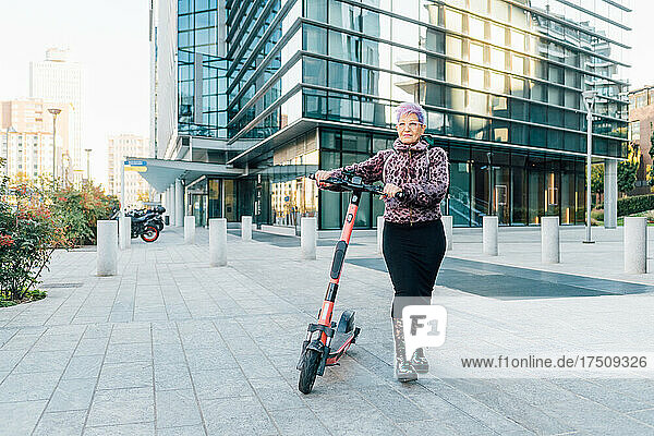 Italy  Fashionable senior woman with push scooter in city