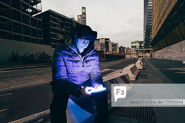 Italy  Man usingVRgoggles in city at dusk
