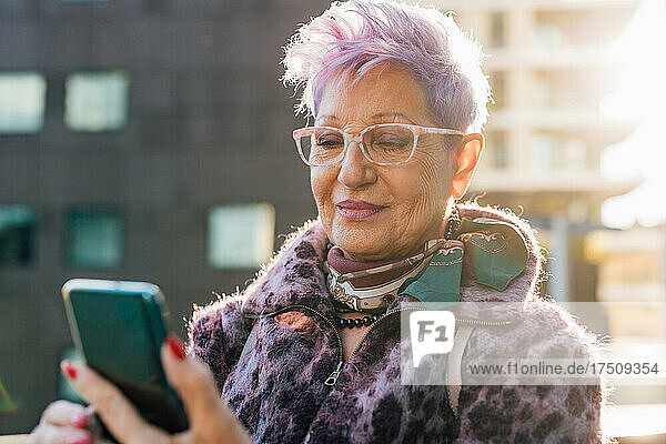 Italy  Fashionable senior woman looking at smart phone in city